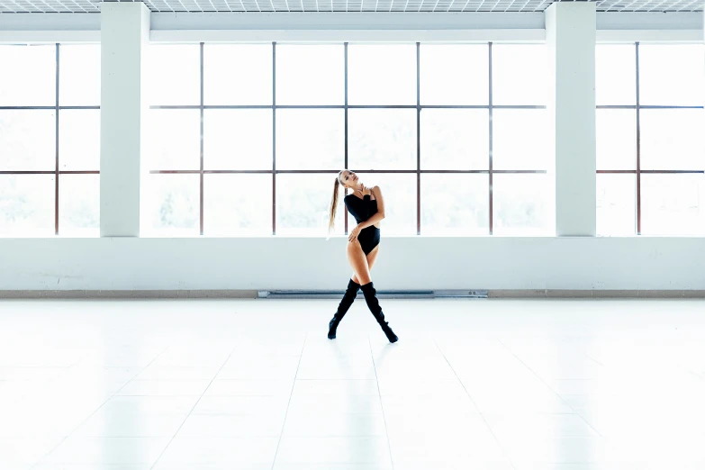 a girl in black clothing is dancing on the white floor