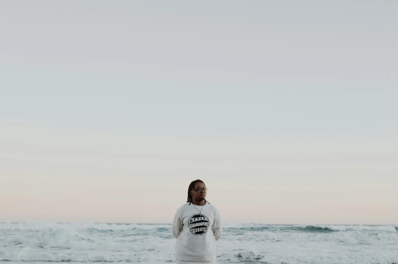 a man standing on the beach with his surfboard