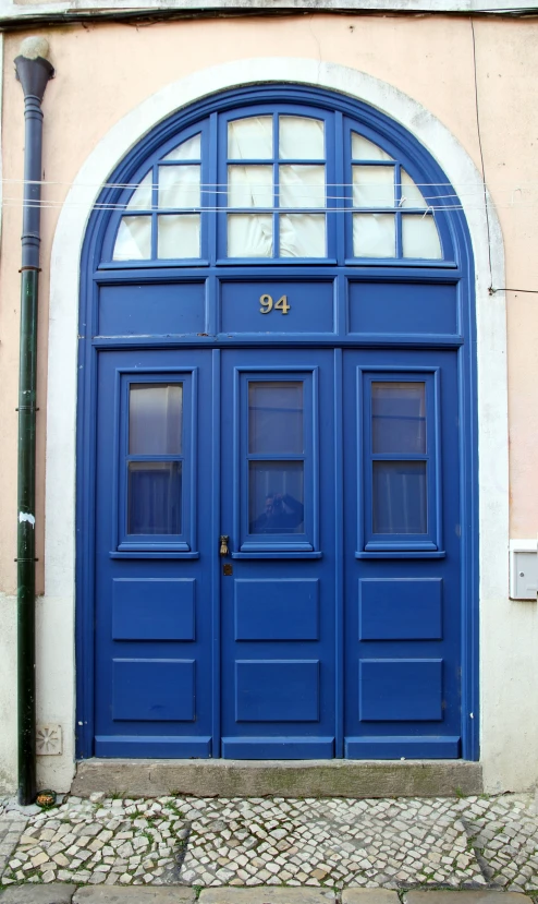 a blue door on an adobe style building with arched glass