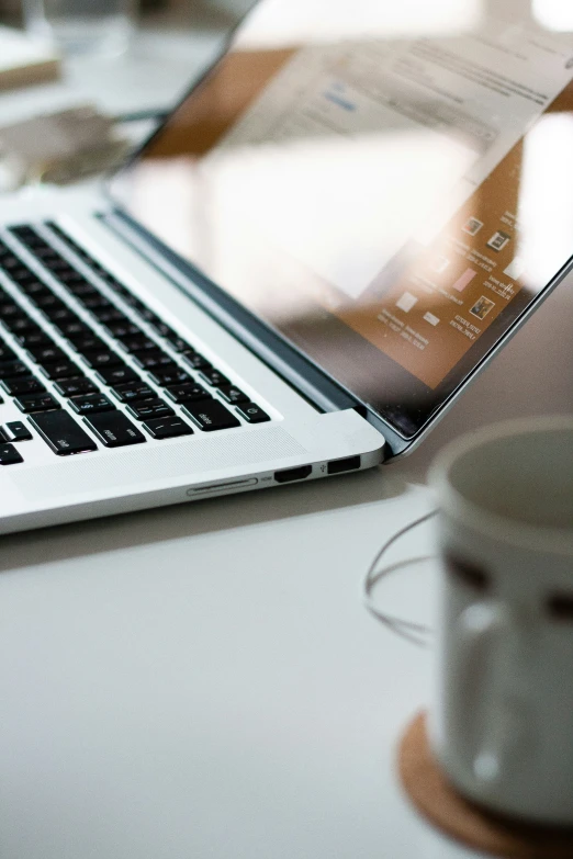 a laptop on a glass table with a cup of coffee