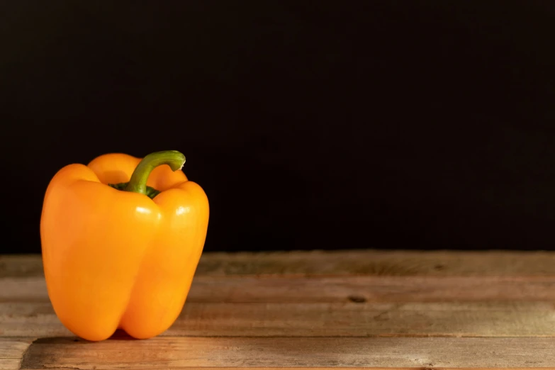 two orange peppers with green leaves on a table