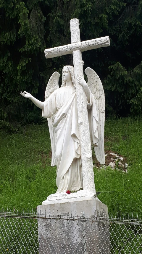 an angel statue sits at the base of a cross