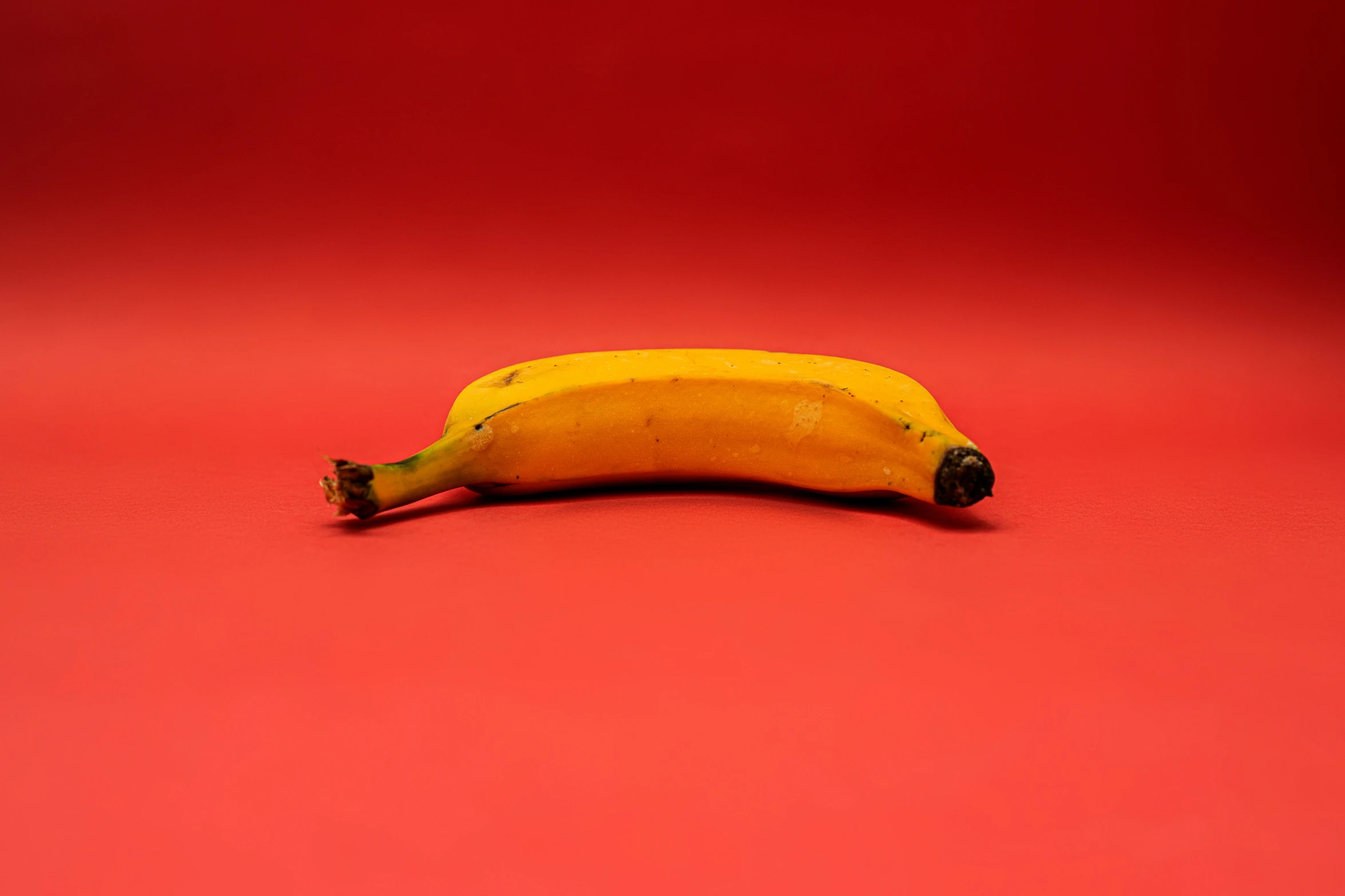 a banana that is laying down against a red backdrop