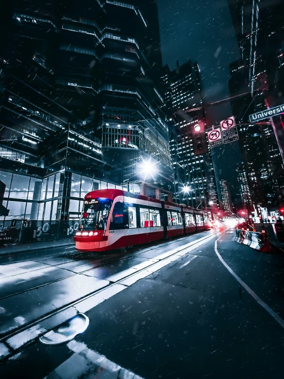 a red and white train traveling down tracks in front of tall buildings