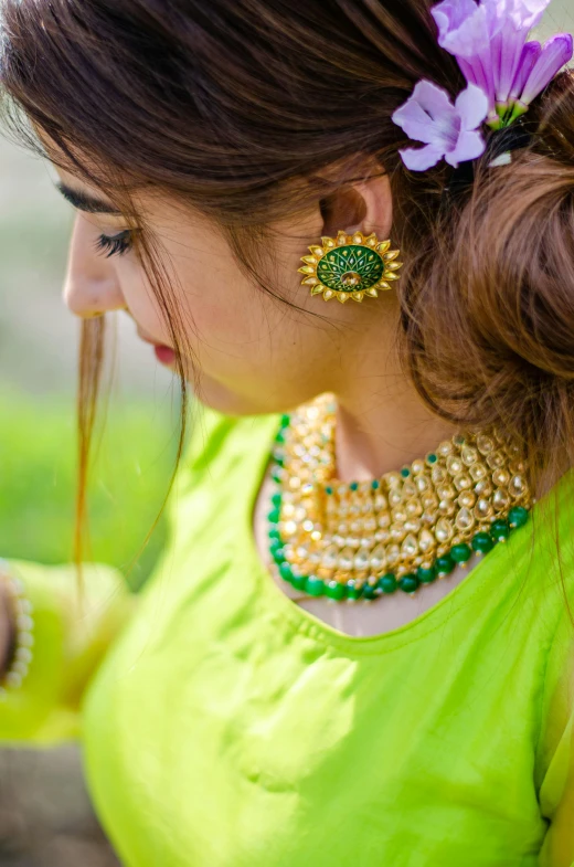 a woman in a green blouse wearing green earrings and holding soing