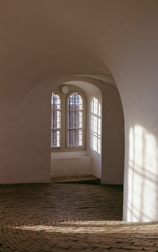 sunlight through two arched windows in an empty room