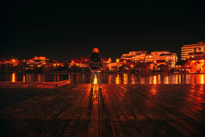 woman standing on dock overlooking water with buildings in background