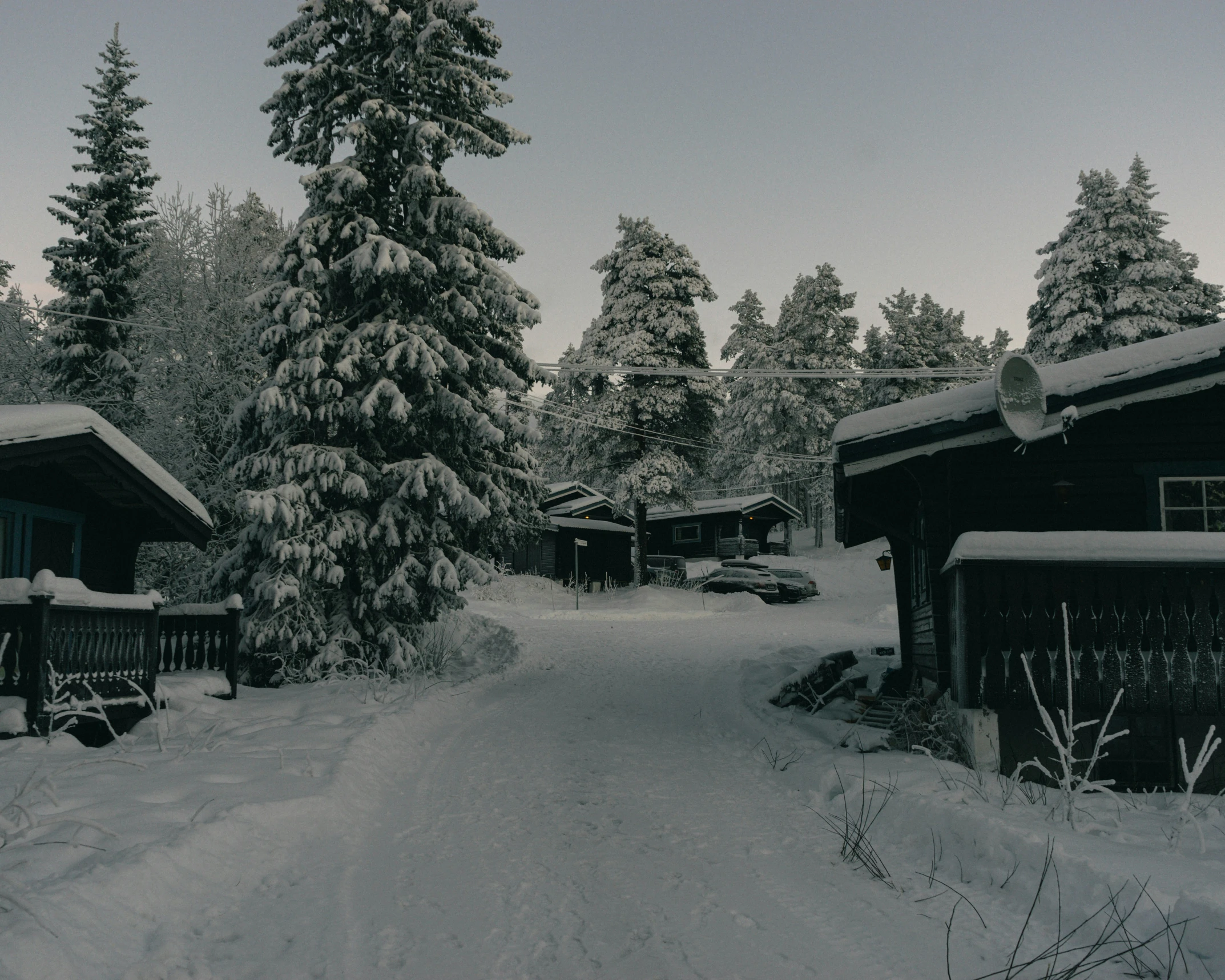 a winter scene of some houses and a snow covered road