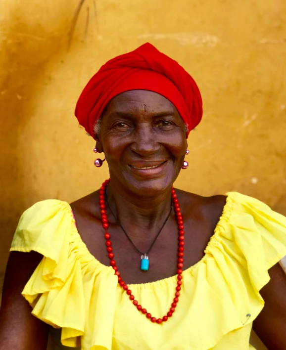 a woman smiling at the camera while wearing a bright red necklace