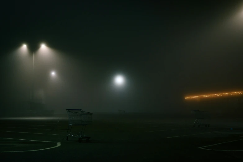 an empty shopping cart sitting in a parking lot with three lights shining at it's end