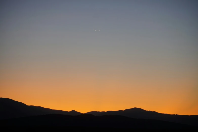 silhouette of mountains and the moon in the distance