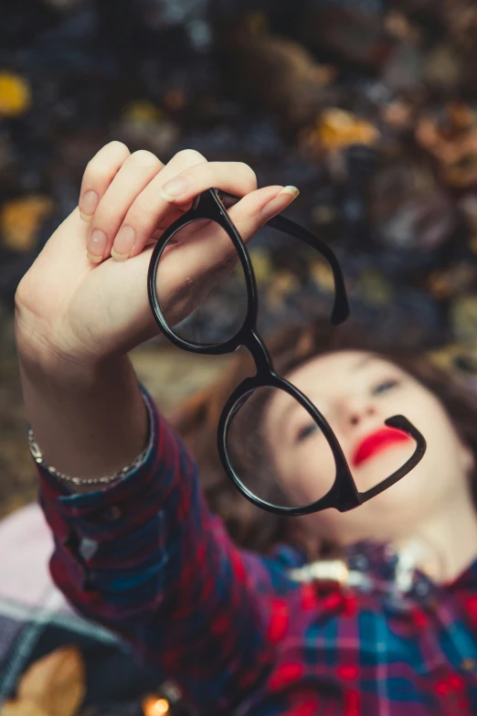 a woman holding up her eyeglasses to take her po