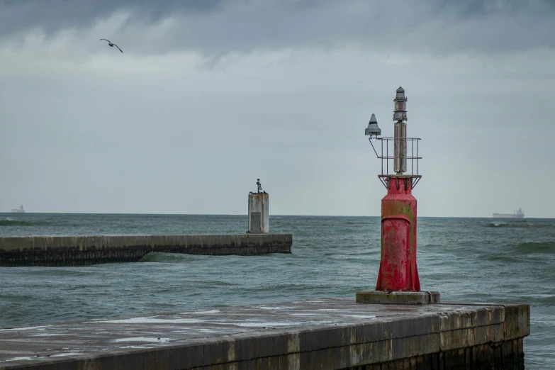 a lighthouse in front of the ocean under a cloudy sky