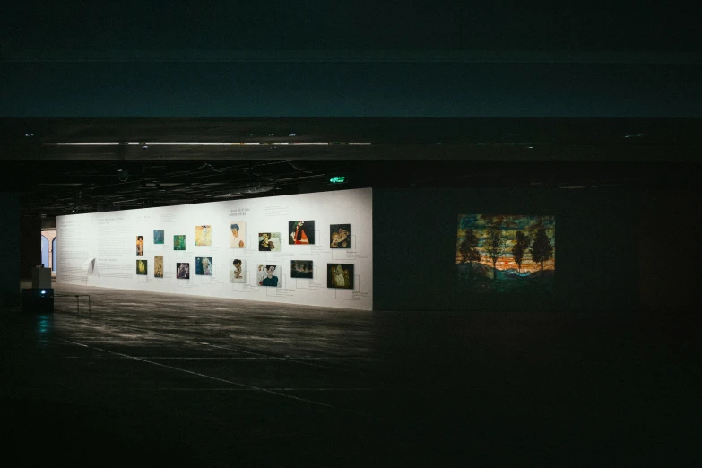 a lit room in the dark with multiple pictures on it