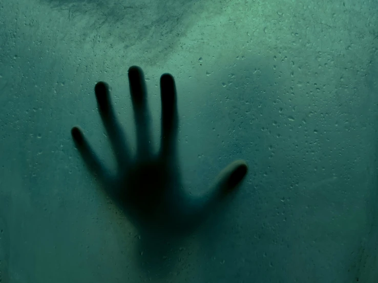 someone holding their hand up in water with the shadow of the hand
