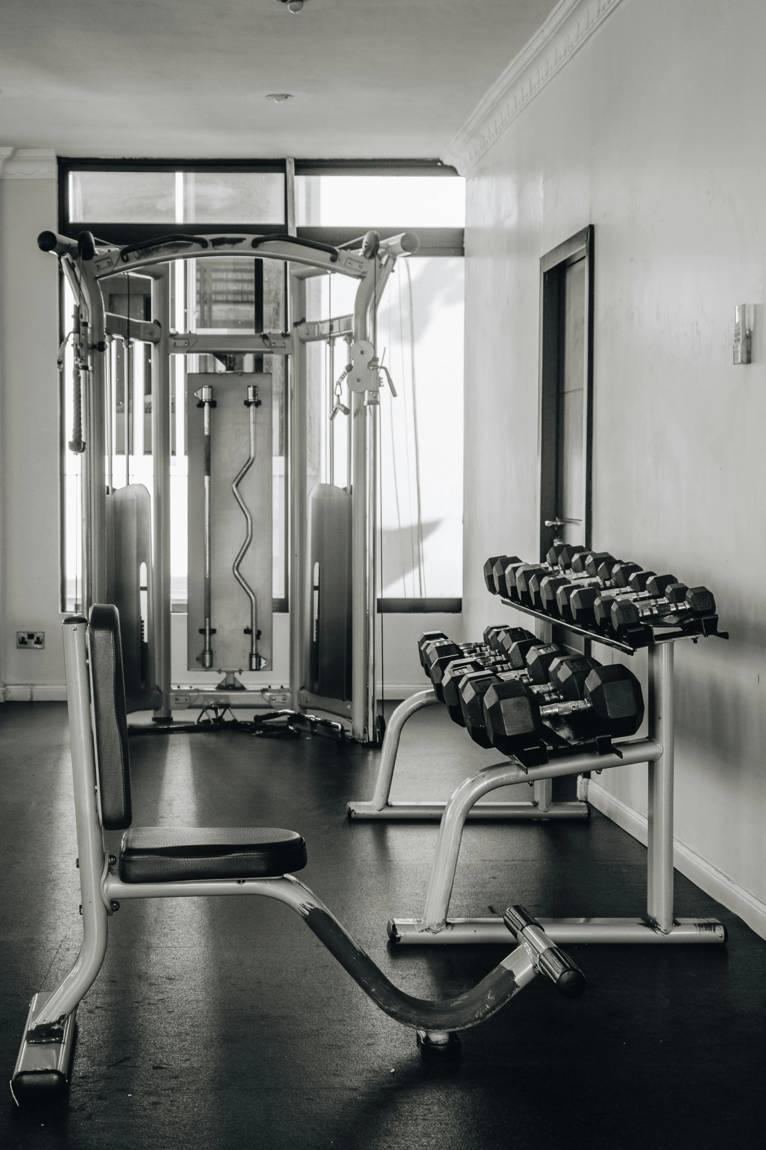 an empty gym with a machine, dumb curls and weights