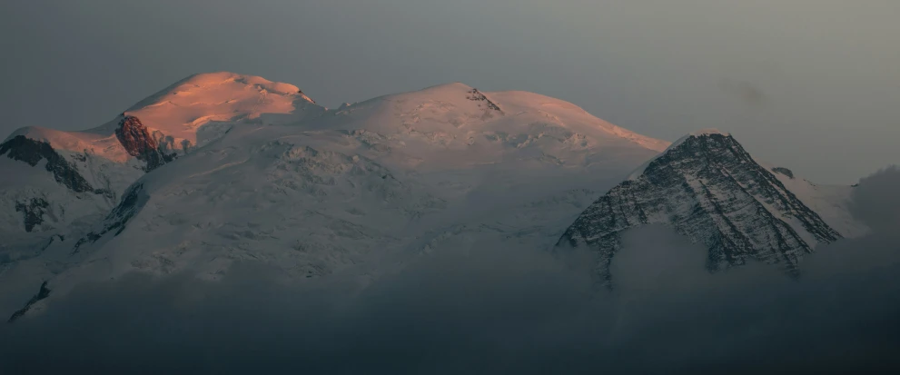 the snow - capped mountains rise into the sky from a distance