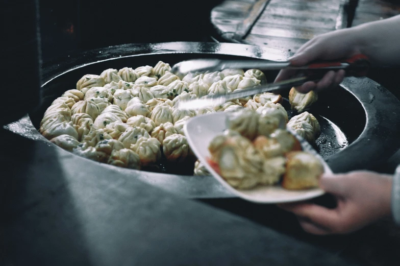 someone is putting fried food in the large frying pan