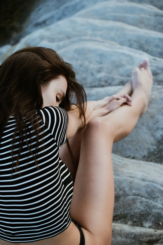 a woman in a black and white  shirt sitting on rocks