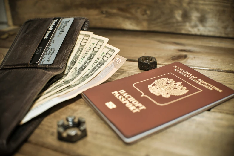 money, passport, and leather wallet laying on the table