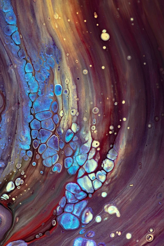 a close up picture of liquid flowing from bubbles into a purple, orange and blue swirled fluid bottle