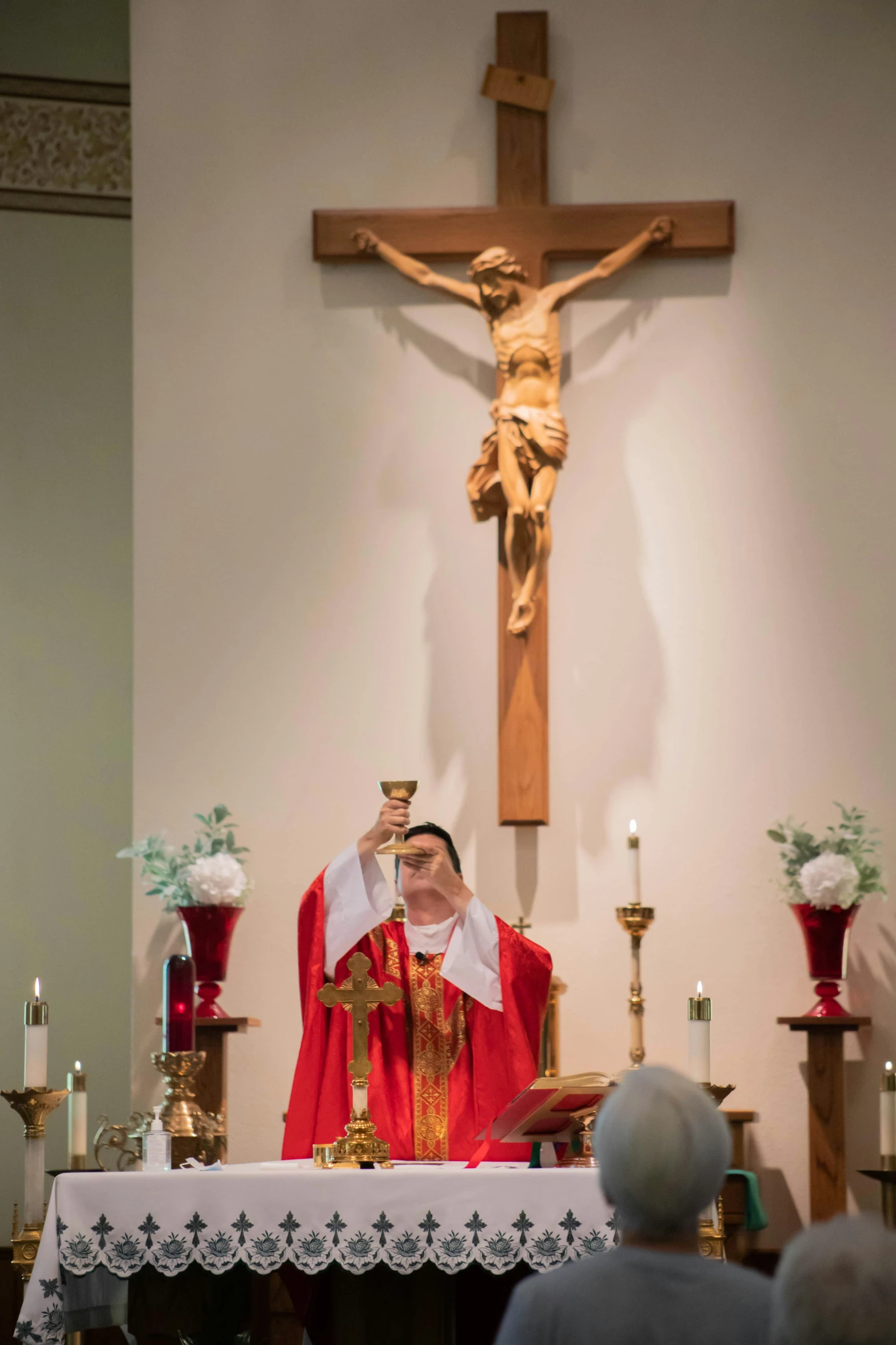 a man wearing red and white standing in front of a wooden cross