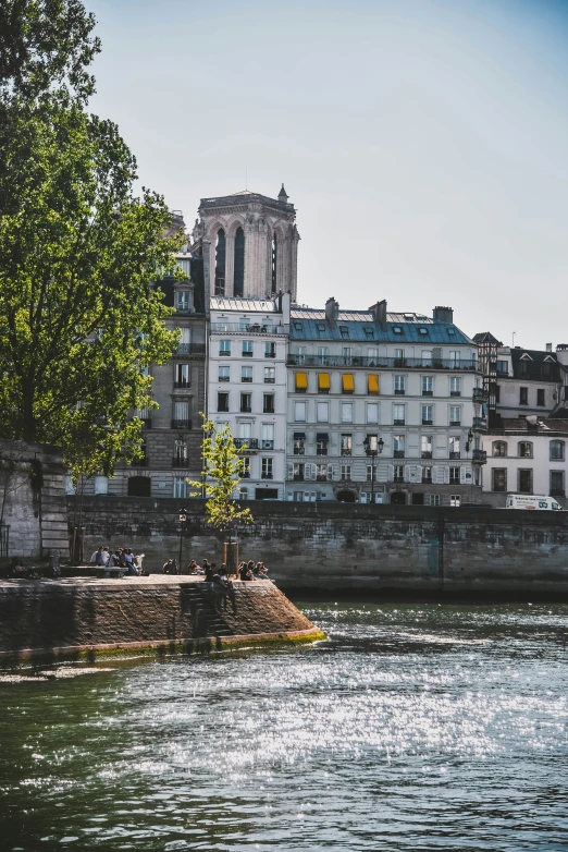 a river with buildings next to it, and a tree in front of a riverbank