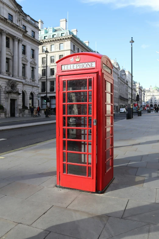 an old - fashioned telephone box is standing alone on the pavement