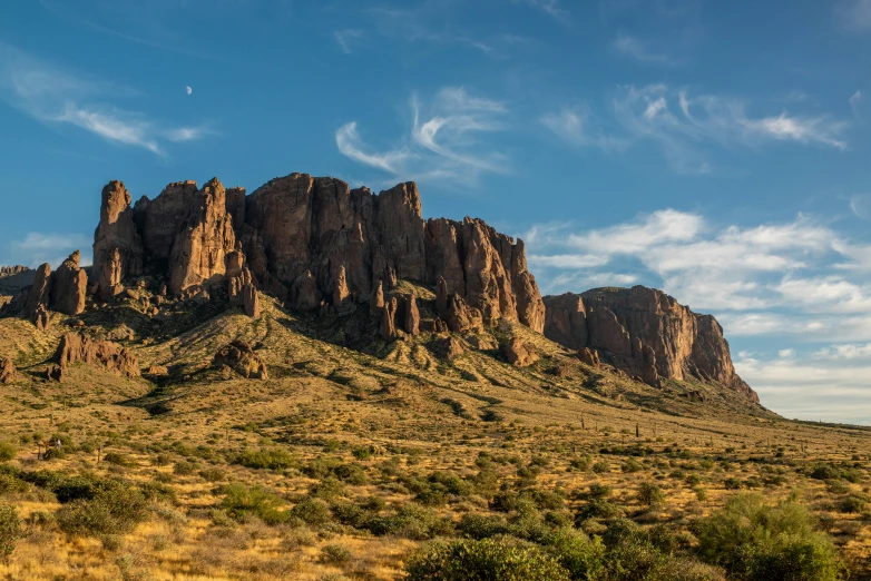 a big mountain sits next to a grassy field