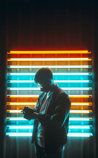 silhouette of man using a cell phone in front of colorful lights
