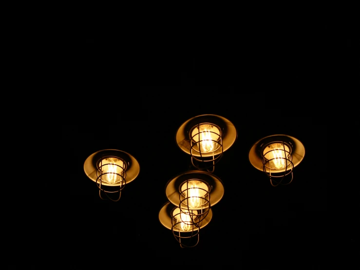 five lit lamps at night on a dark surface