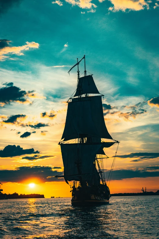 a sail boat sailing across the ocean at sunset