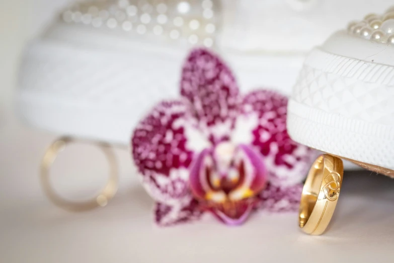 a ring rests among other gold wedding jewelry, including a flower