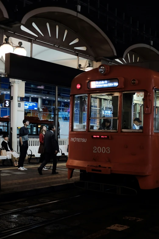 people on the platform at night, with a train passing