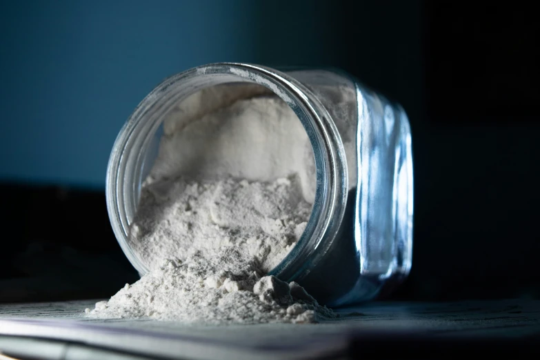 a jar that is sitting next to a pile of white powder