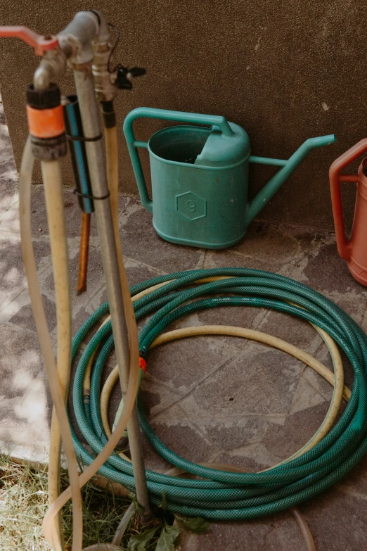 two watering hoses next to each other and a garden watering tool