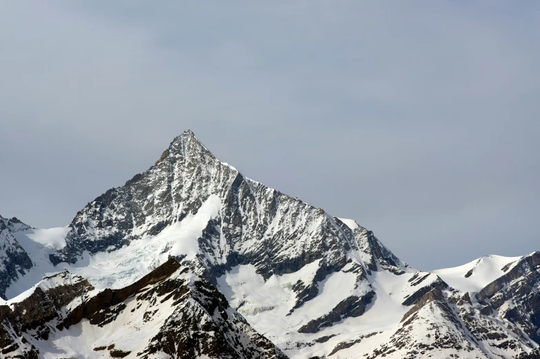 some very tall mountains covered in snow with some clouds