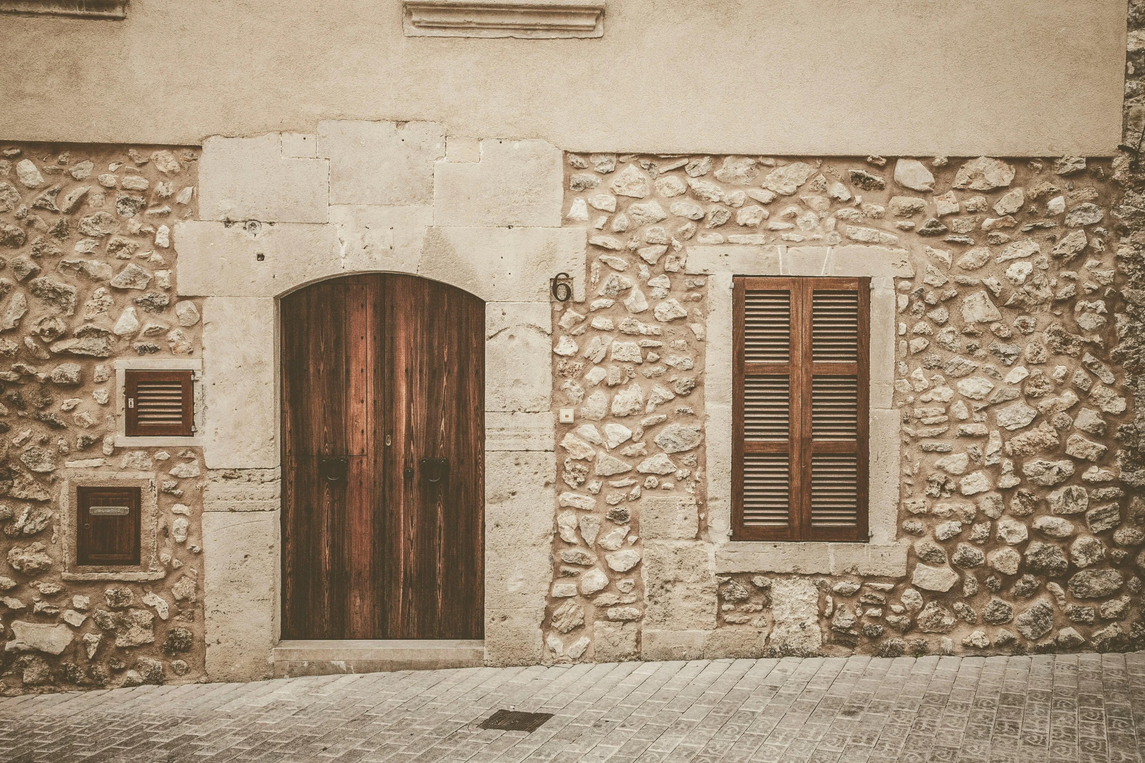 an old building with wood doors, windows and shutters