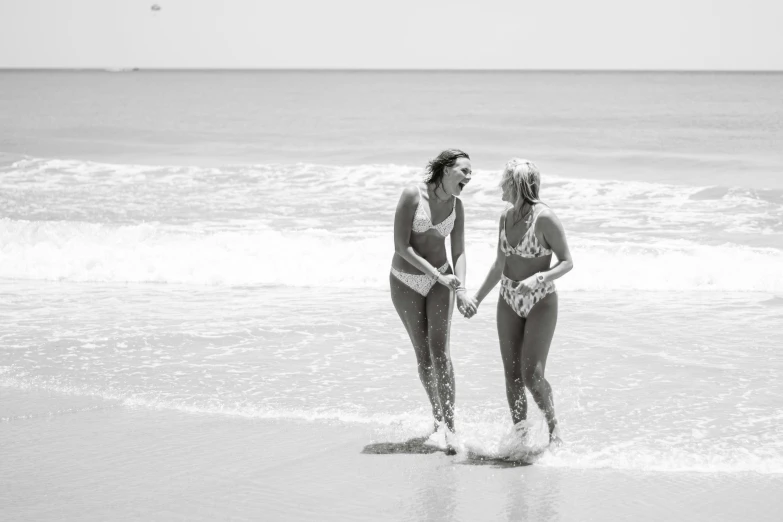 two young women walking out to the ocean