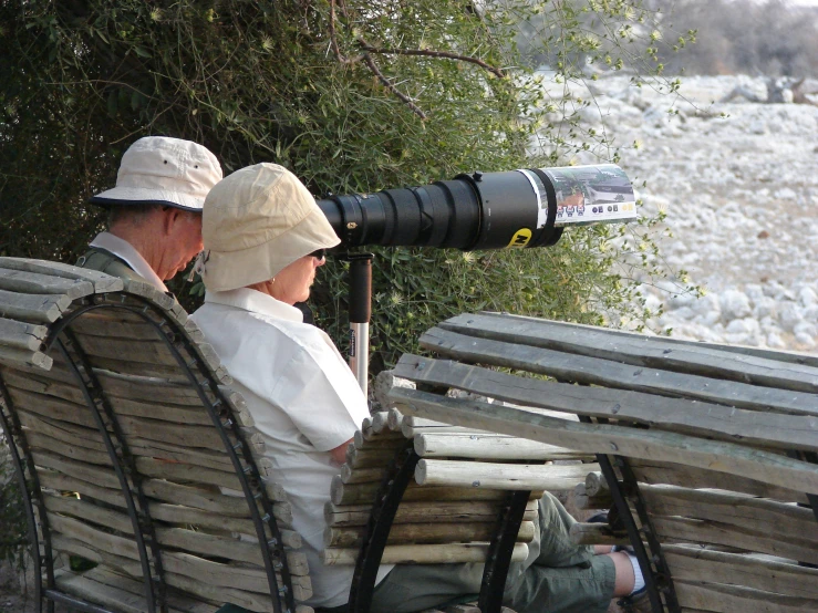 a couple sitting on a bench with camera gear