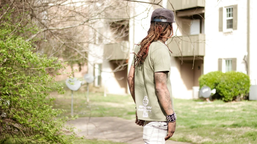 a young man holding his skateboard in front of some apartments