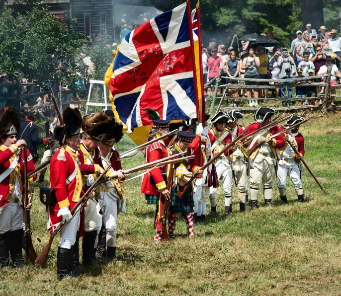 some men dressed in british military uniforms are marching down a field