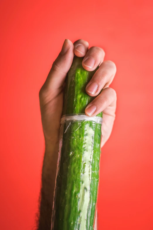 a person holding a large cucumber in their right hand