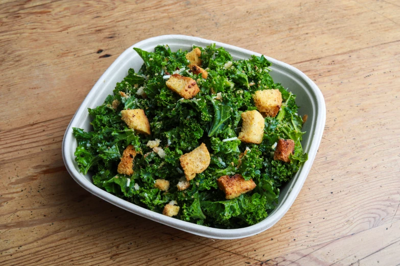 a bowl filled with green salad on top of a table