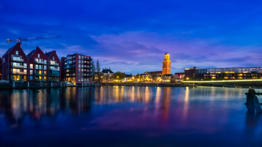 buildings are reflected in the still water in the river at night