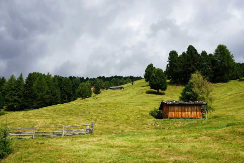 a wooden cabin on top of a hill with a fence