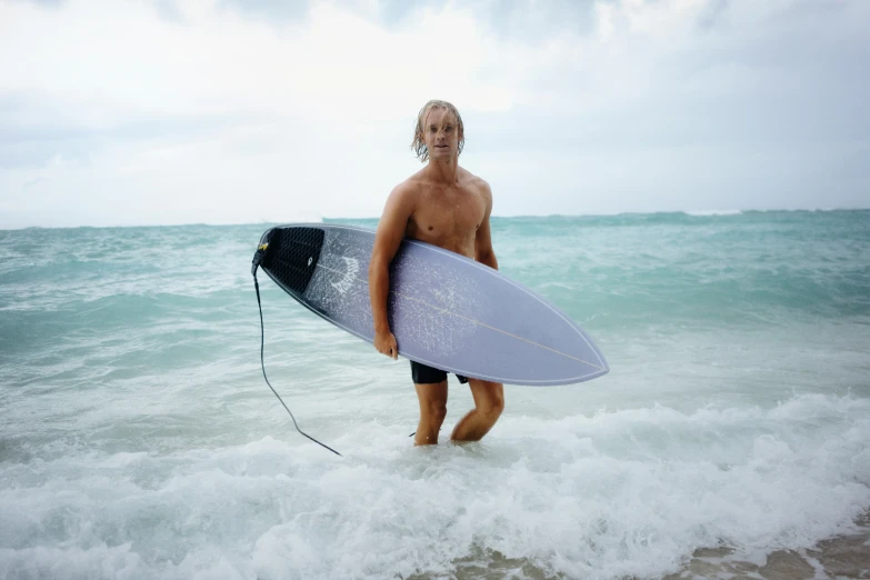 a man with a surfboard standing in the waves