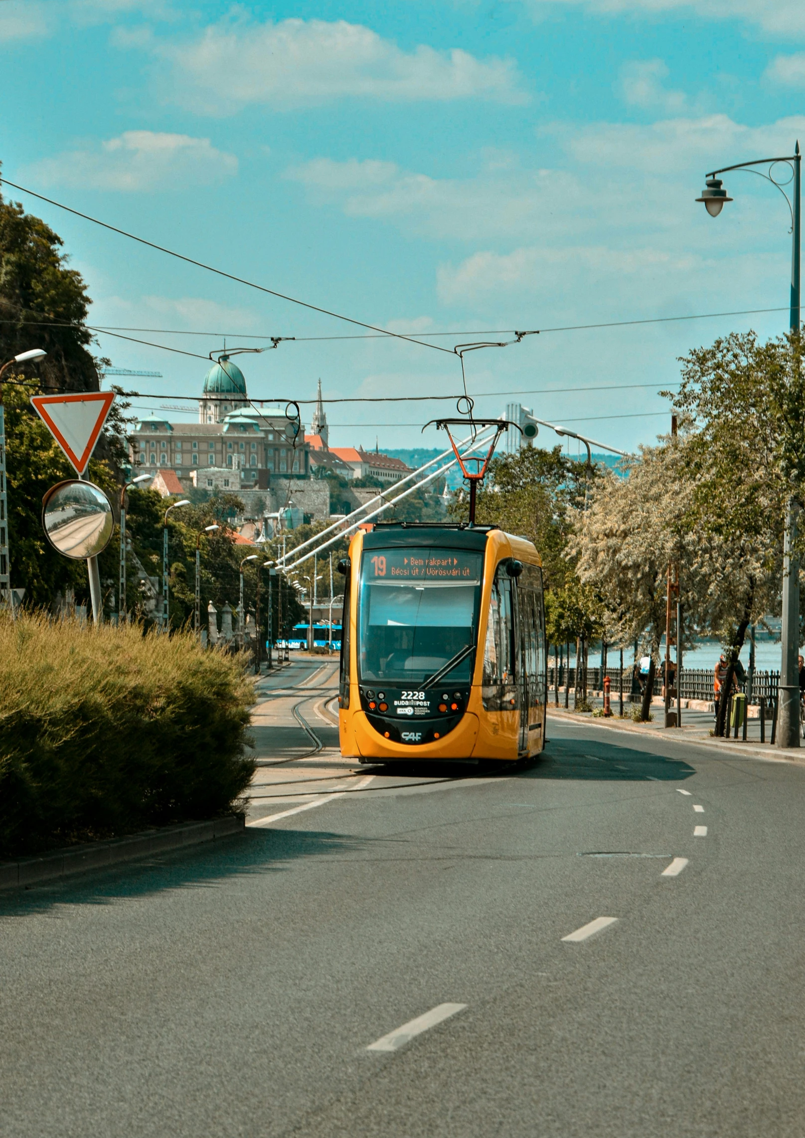 a yellow trolley car is going down the street