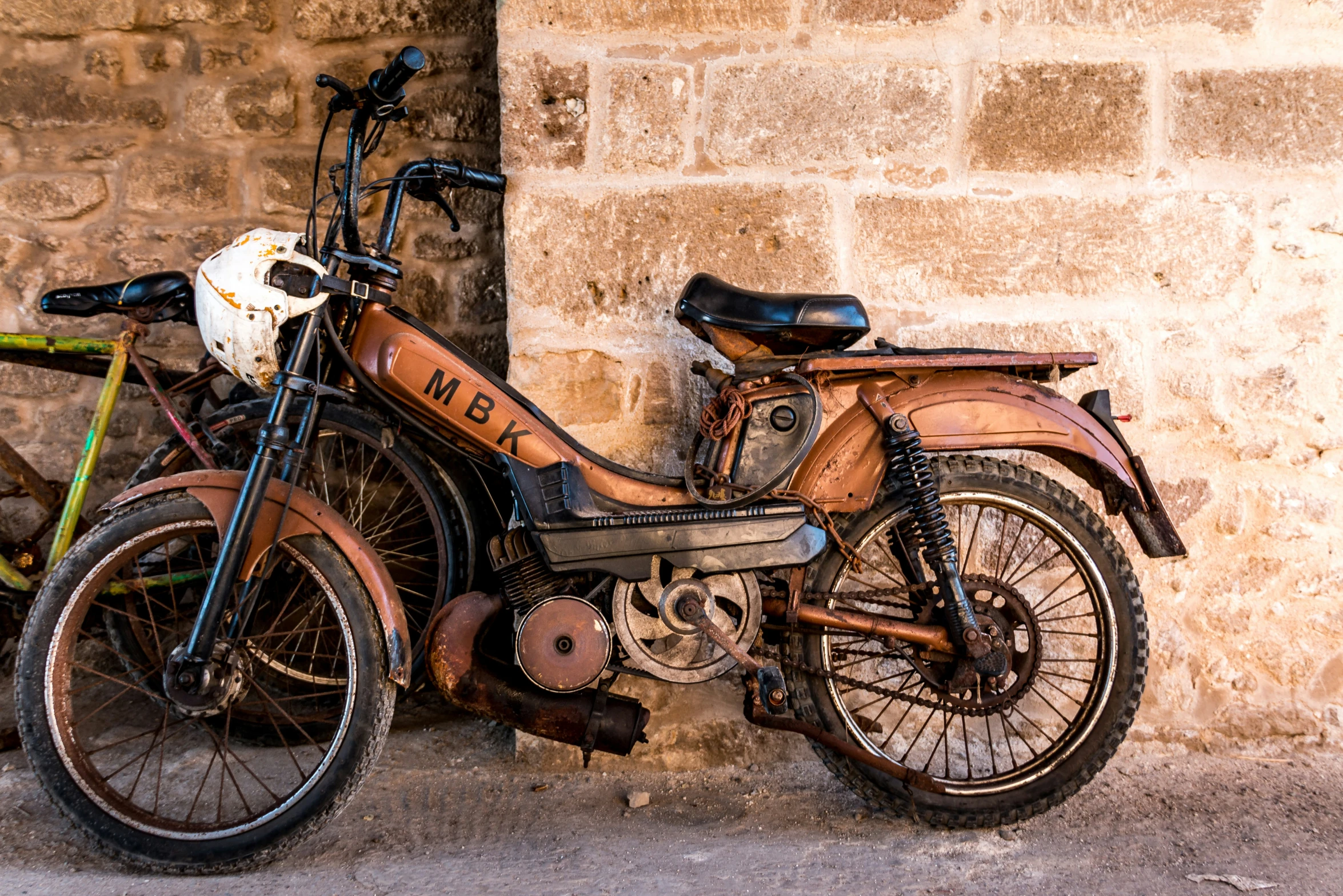 an old motor bike against the side of a brick wall