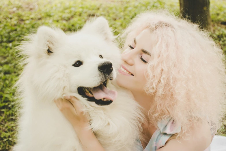 a woman is holding a large white dog in a grassy area